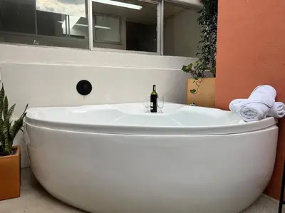 a white bath tub with a bottle of wine in a bathroom at Apto BBC With Jacuzzi In Heart Of Provenza in Medellín