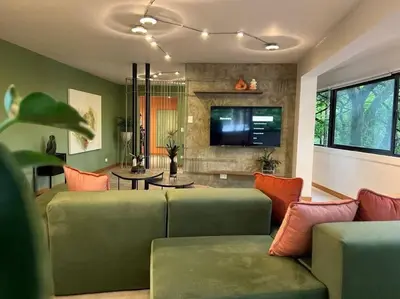a living room with a green couch and a tv at Apto BBC With Jacuzzi In Heart Of Provenza in Medellín