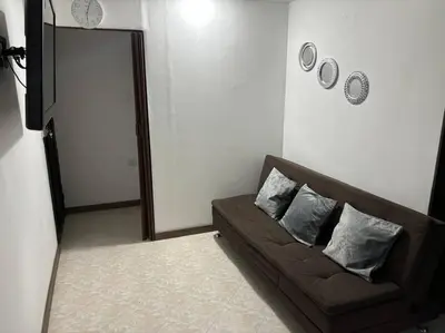 a living room with a brown couch with two pillows at Apartamento en Bello Medellín in Bello