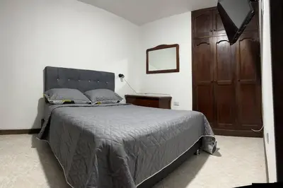a bedroom with a large bed and a wooden cabinet at Apartamento en Bello Medellín in Bello