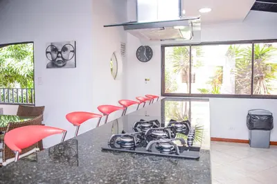 a kitchen with red stools and a counter with a stove at Apartment El Jeffe Medellin in Medellín