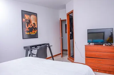 a bedroom with a bed and a flat screen tv at Apartment El Jeffe Medellin in Medellín
