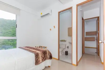 a white bedroom with a bed and a bathroom at Apartamento Vacacional San Jeronimo Paraíso Bali in San Jerónimo