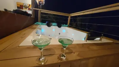 two wine glasses sitting on a table next to a bath tub at Mayka cabañas con JACUZZI in Guatapé