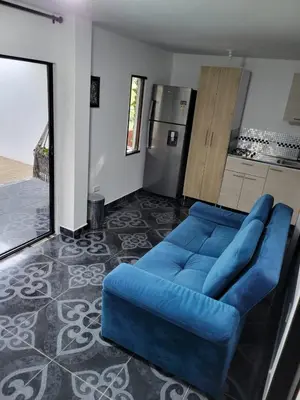 a blue couch in a living room with a kitchen at Mayka cabañas con JACUZZI in Guatapé