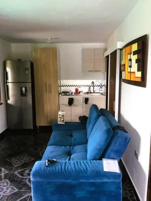 a blue couch in a living room with a kitchen at Mayka cabañas con JACUZZI in Guatapé