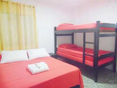 a room with two bunk beds with red sheets at Central y privado a 1km de la hacienda Nápoles in Doradal