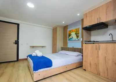 a bedroom with a large bed and a kitchen at Hotel Lares 70 Laureles in Medellín