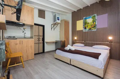 a bedroom with a large bed and a kitchen at Hotel Lares 70 Laureles in Medellín