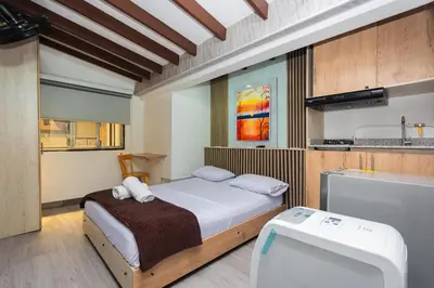 a small bedroom with a bed and a kitchen at Hotel Lares 70 Laureles in Medellín