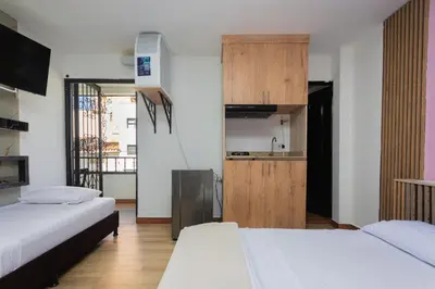 a room with two beds and a small kitchen at Hotel Lares 70 Laureles in Medellín