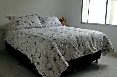 a bed with a comforter on it in a bedroom at APARTAMENTO PRIVADO Y TRANQUILO EN MANILA. in Medellín