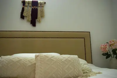 a bed with a white blanket and tassels on the wall at Eco Apartamento Crudo in Jardin