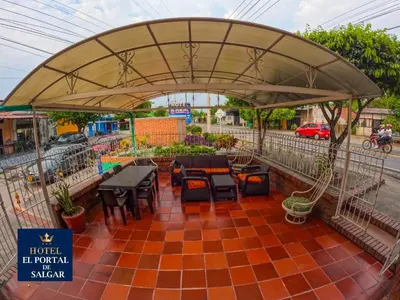 a patio with tables and chairs under an umbrella at Hotel El Portal de Salgar in Puerto Salgar