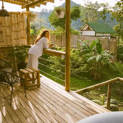 a woman standing at a table on a deck at Cabaña Glamping San Carlos Antioquía Pun chinaw Ecocabañas in San Carlos