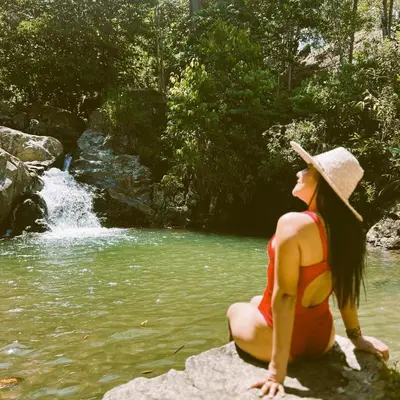 a woman in a bikini sitting on a rock near a river at Cabaña Glamping San Carlos Antioquía Pun chinaw Ecocabañas in San Carlos