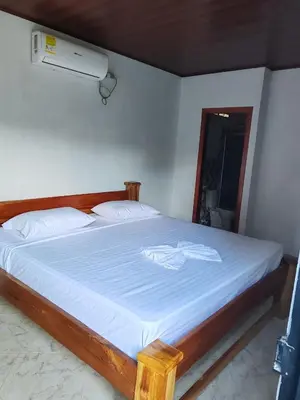 a bedroom with a bed with white sheets and a fan at Finca Campestre La Flor in Doradal