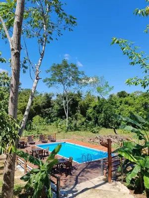 a pool with tables and chairs next to a forest at Finca Campestre La Flor in Doradal