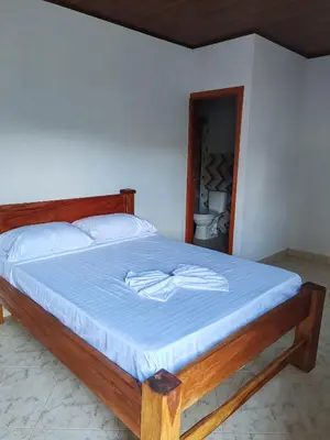 a bedroom with a bed with a blue bedsheet and a bathroom at Finca Campestre La Flor in Doradal