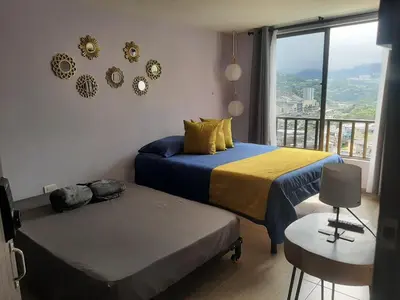 a bedroom with two beds and a balcony with a view at Suite con hamaca y baño privado. in Manizales