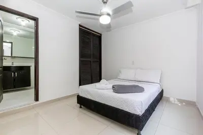 a white bedroom with a bed and a large window at ¡Apartamento HOME LAURELES excelente ubicación! in Medellín