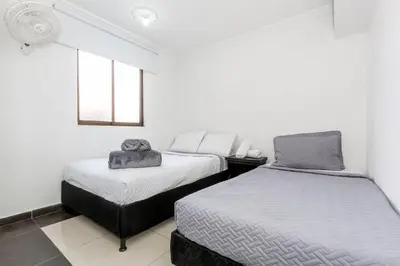 a white room with two beds and a window at ¡Apartamento HOME LAURELES excelente ubicación! in Medellín