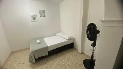 a small bed in a room with a fan at APARTAHOTEL ESTADIO GOLD in Medellín