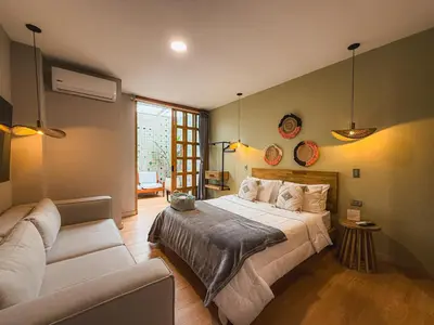 a bedroom with a large bed and a couch at M de oro Apartamentos Muuk boutique POBLADO in Medellín
