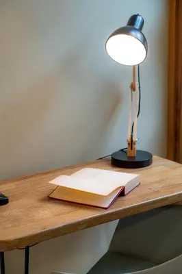 a desk with a lamp and a book on it at M de oro Apartamentos Muuk boutique POBLADO in Medellín