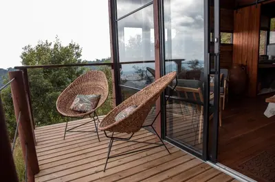 two chairs sitting on a deck with glass doors at Owl's Watch at Rio Blanco in Manizales