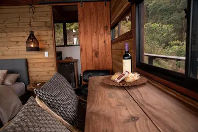 a room with a wooden table with a bottle of wine at Owl's Watch at Rio Blanco in Manizales