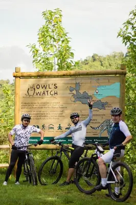 a group of three people on bikes in front of a sign at Owl's Watch at Rio Blanco in Manizales