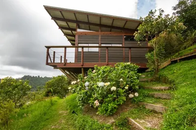 a house on the side of a hill with flowers at Owl's Watch at Rio Blanco in Manizales