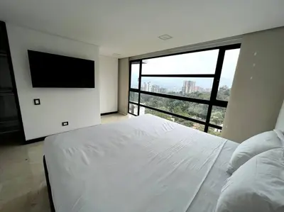 a bedroom with a white bed and a flat screen tv at 501 Luxury Apartment In Heart Of El Poblado in Medellín