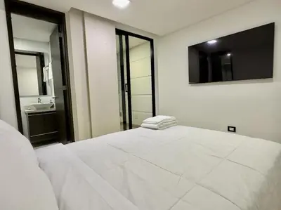 a white bed in a room with a bathroom at 1401, Luxury Penthouse In El Poblado in Medellín