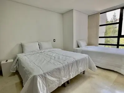 a white bedroom with two beds and a window at 602, Modern apartment in heart of El Poblado + View! in Medellín