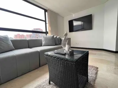 a living room with a couch and a table with a tv at 602, Modern apartment in heart of El Poblado + View! in Medellín