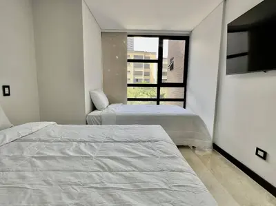 a bedroom with two beds and a tv and a window at 602, Modern apartment in heart of El Poblado + View! in Medellín