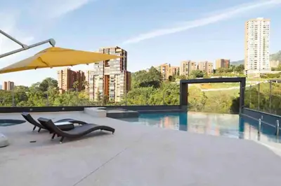 a patio with a pool and an umbrella and chairs at 602, Modern apartment in heart of El Poblado + View! in Medellín