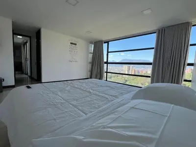 a large white bed in a room with a large window at 1202, Central Apartment in El Poblado + View in Medellín