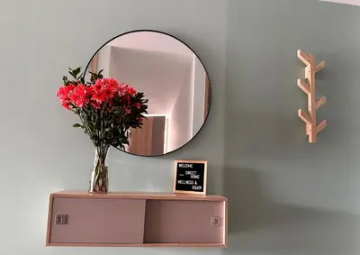 a vase of red flowers on a table with a mirror at Aluna Apto/ Wellness and Enjoy in Sabaneta