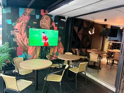 a restaurant with tables and chairs and a large screen at Provenza Medellin Hotel Boutique in Medellín