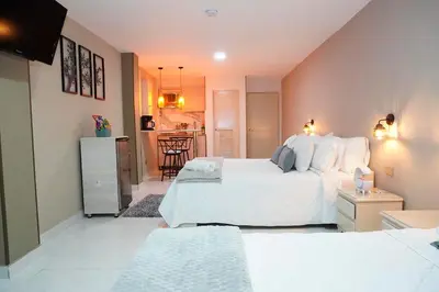 a bedroom with a large white bed and a kitchen at Provenza Medellin Hotel Boutique in Medellín