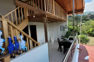 a balcony of a house with a table and chairs at Luz de Luna - Hermosa Finca Familiar con Vista Panorámica y de Aves in Cocorná