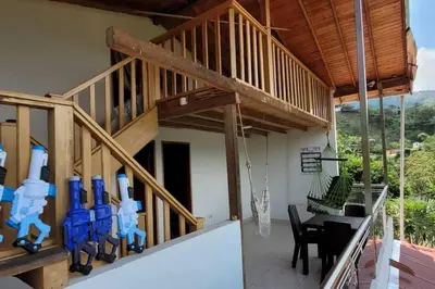 a balcony of a house with a table and chairs at Luz de Luna - Hermosa Finca Familiar con Vista Panorámica y de Aves in Cocorná