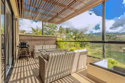 a balcony with wicker furniture and a view of the mountains at San Telmo Lake Guatape view in Guatapé