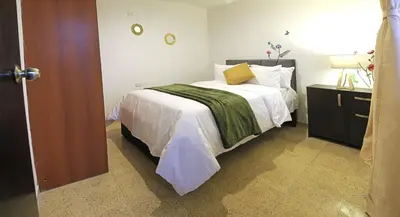 a bedroom with a bed with white sheets and yellow pillows at Familiar y acogedor in Medellín