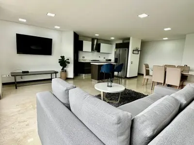 a living room with a large couch and a kitchen at 302 Spacious apartment nice view in El Poblado in Medellín