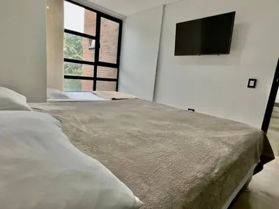 a bedroom with a bed with a flat screen tv on the wall at 502 El Poblado: Beautiful & ample space for families in Medellín