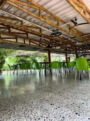 a group of green tables and chairs under a wooden roof at Hotel Chicala salgar in Puerto Salgar